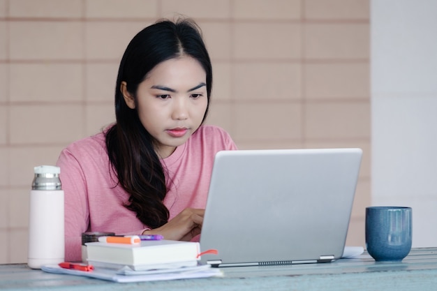 Młoda azjatycka, niezależna bizneswoman pracująca na laptopie w domu podczas pandemii COVID-19. Dorosła osoba ucząca się online w domu. Zdjęcie stockowe