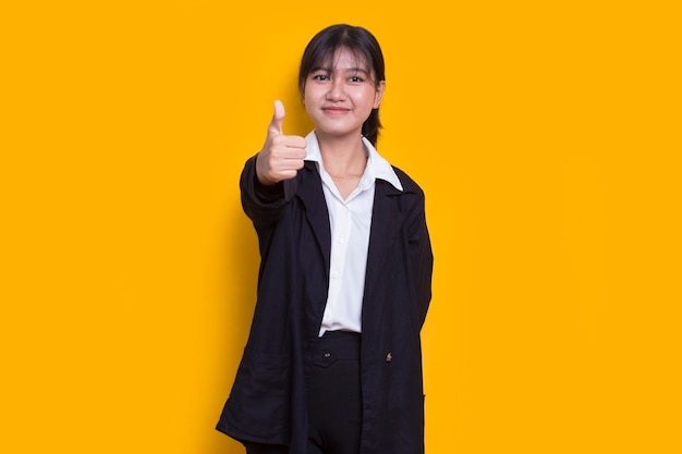 młoda azjatycka piękna kobieta z ok znak gestem tumb up na białym tle na żółtym tle