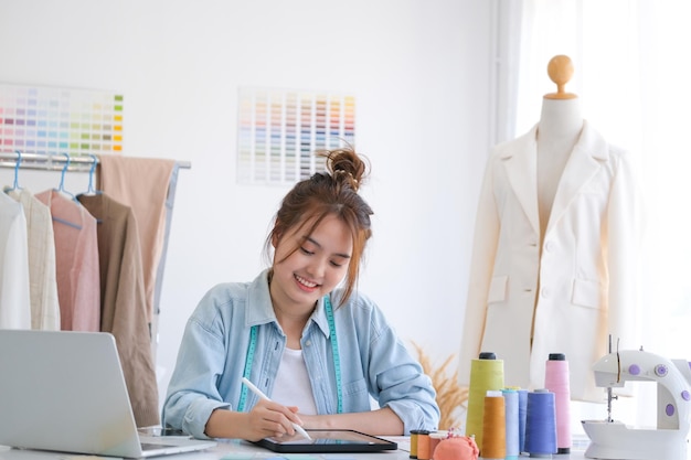 Młoda azjatycka projektantka mody projektująca kolekcję mody na tablecie