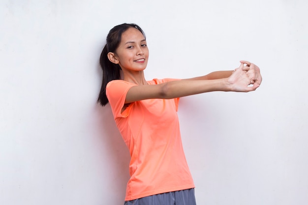 Młoda azjatycka sportowa kobieta robi rozciąganie na białym tle