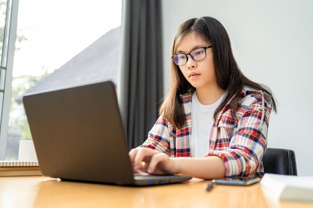 Młoda azjatycka studentka pracuje i uczy się zdalnie z domu podczas zamknięcia miasta