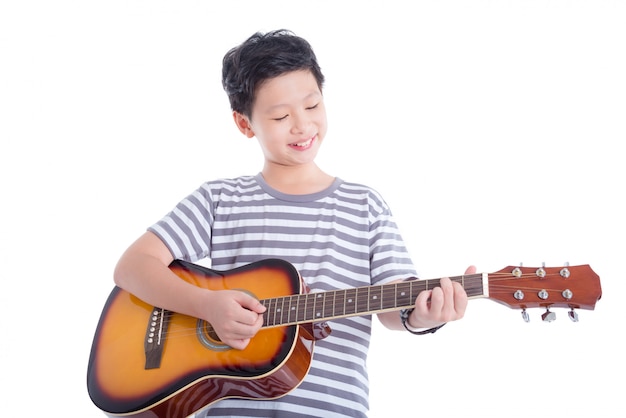 Młoda azjatykcia chłopiec bawić się gitarę i uśmiechy nad białym tłem