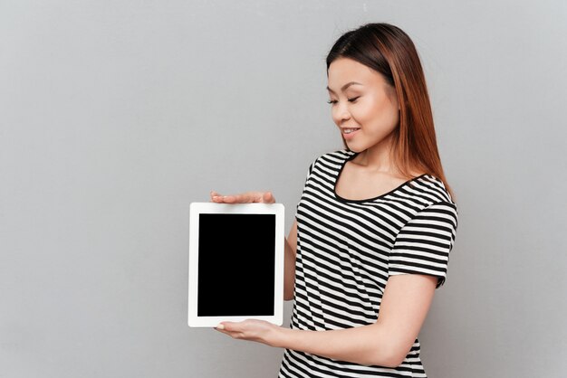 Młoda azjatykcia kobieta pokazuje pastylkę z pustym ekranem