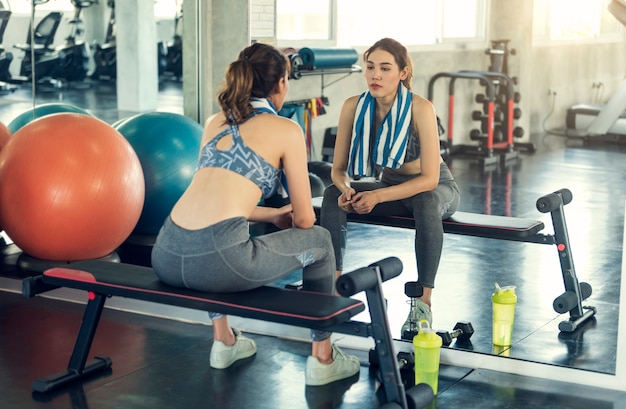 Młoda azjatykcia sporty kobieta męcząca siedzieć z ręcznikiem po gym treningu w sprawności fizycznej.