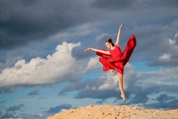 Młoda Balerina W Czerwonej Sukience Zamarła W Skoku Na Błękitne Niebo