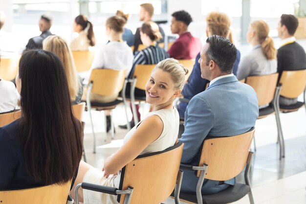 Zdjęcie młoda biała bizneswoman siedziała w sali konferencyjnej uśmiechając się do kamery