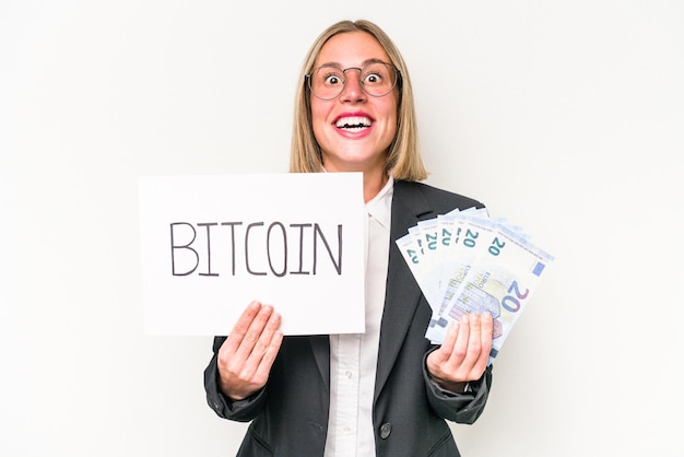 Młoda biznesowa kobieta rasy kaukaskiej trzymająca tabliczkę z bitcoinami i banknoty na białym tle