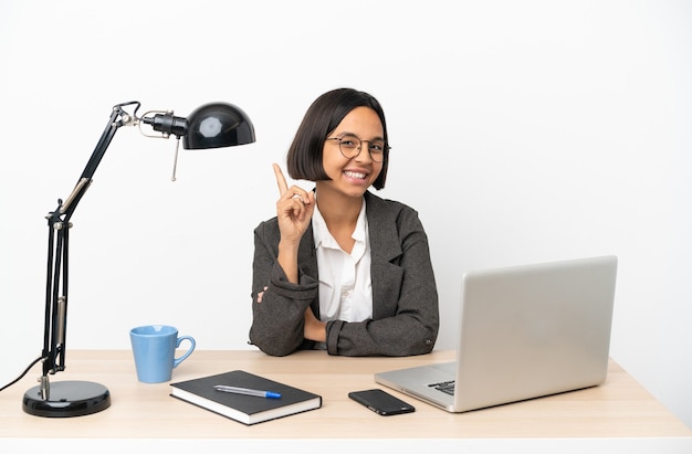 Młoda biznesowa kobieta rasy mieszanej pracująca w biurze pokazująca i podnosząca palec na znak najlepszych