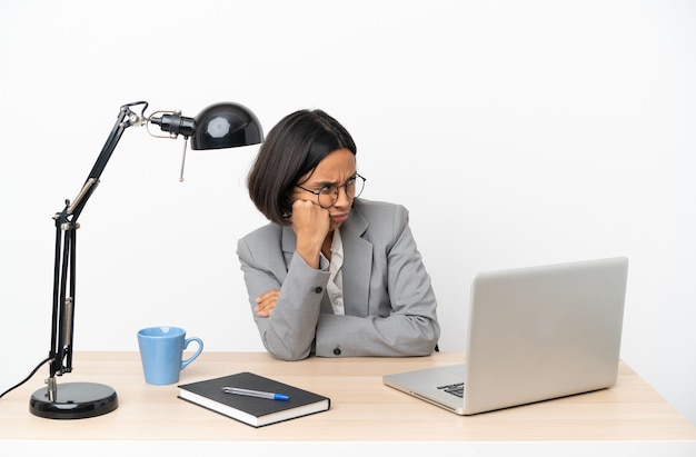 Młoda biznesowa kobieta rasy mieszanej pracująca w biurze ze zmęczoną i znudzoną miną
