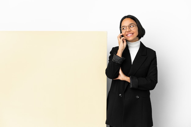 Młoda biznesowa kobieta rasy mieszanej z dużym banerem na białym tle prowadzenie rozmowy z telefonem komórkowym