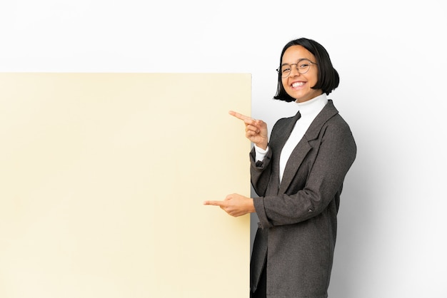 Młoda biznesowa kobieta rasy mieszanej z dużym banerem na białym tle, wskazująca palcem na bok i prezentująca produkt