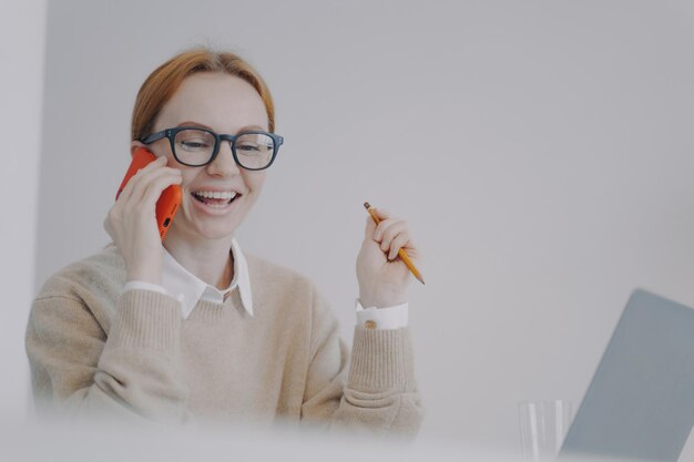 Młoda biznesowa kobieta rozmawia przez telefon i śmieje się Konferencja telefoniczna i komunikacja