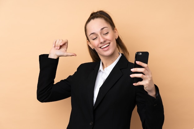Młoda biznesowa kobieta używa telefon komórkowego nad odosobnioną ścianą dumną i samozadowoloną