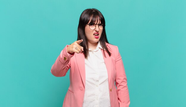 Młoda biznesowa kobieta wskazująca na kamerę z wściekłym, agresywnym wyrazem twarzy, wyglądająca jak wściekły, szalony szef
