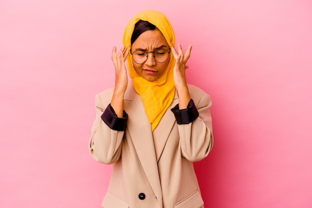 Młoda biznesowa muzułmańska kobieta na białym tle na różowym tle dotyka świątyń i ma ból głowy.