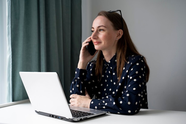 Zdjęcie młoda bizneswoman jest menedżerem pracującym przy laptopie i wykonującym telefony w biurze profesjonalistą