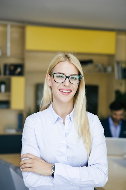 Młoda bizneswoman pozycja w biurze i innych młodzi ludzie biznesu pracuje w tle