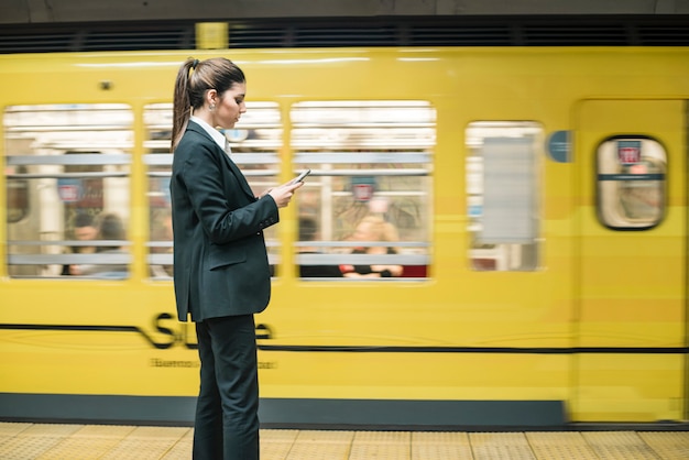 Zdjęcie młoda bizneswoman pozycja z przodu poruszającego metra używa telefon komórkowego