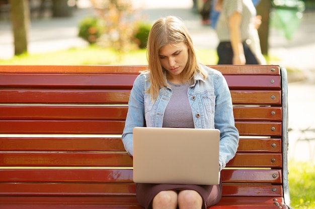 Młoda bizneswoman siedzi w parku i pracuje z laptopem
