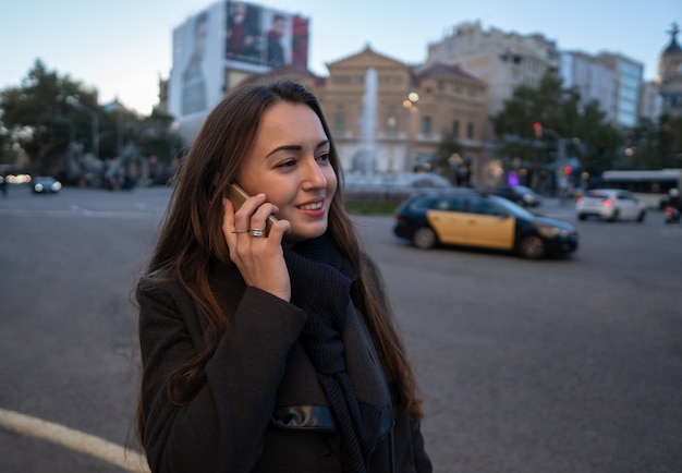 Młoda bizneswoman spacerująca po placu i rozmawiająca przez telefon