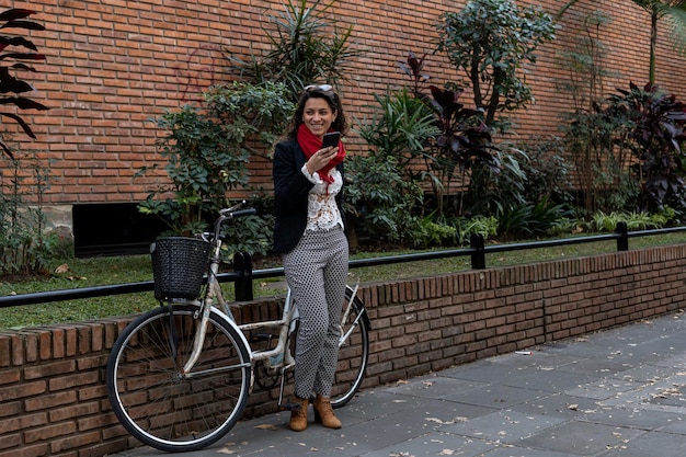Młoda bizneswoman z Ameryki Łacińskiej stojąca obok swojego zabytkowego roweru wysyła wiadomość głosową