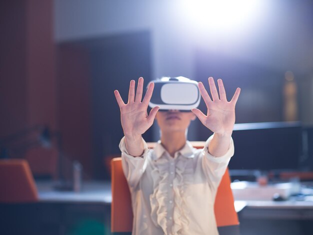 młoda bizneswoman zdobywająca doświadczenie w korzystaniu z okularów wirtualnej rzeczywistości w zestawach słuchawkowych VR w biurowcu startowym późną nocą
