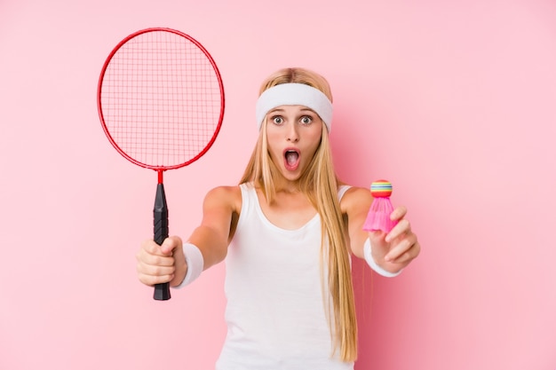 Młoda blond kobieta gra w badmintona na białym tle