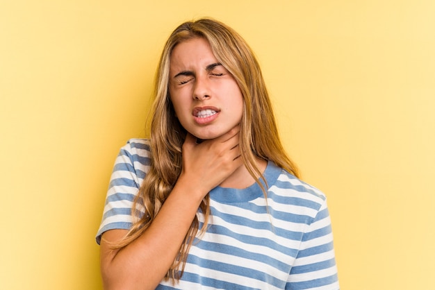 Młoda blond kobieta kaukaski na białym tle na żółtym tle cierpi na ból gardła z powodu wirusa lub infekcji.