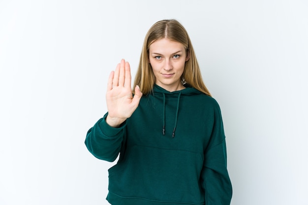 Młoda blond kobieta na białym stojącym z wyciągniętą ręką pokazano znak stopu na białym tle, uniemożliwiając ci.