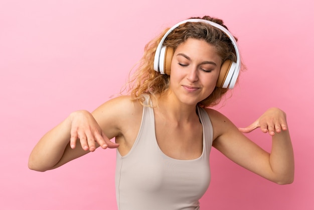Młoda Blond Kobieta Na Różowym Tle Słucha Muzyki I Tańczy