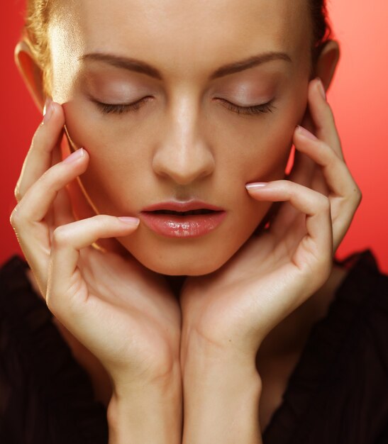 Zdjęcie młoda blond kobieta pozuje z zamkniętymi oczami na czerwonym tle, uroda i moda koncepcja. ścieśniać.