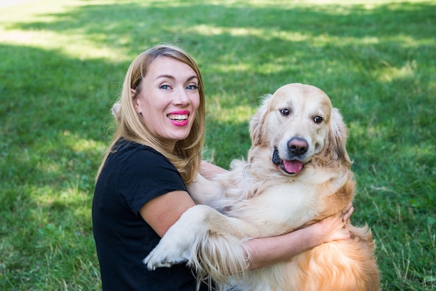 Młoda Blond Kobieta Przytula Swojego Psa Retriever Na Zewnątrz. Zbliżenie.