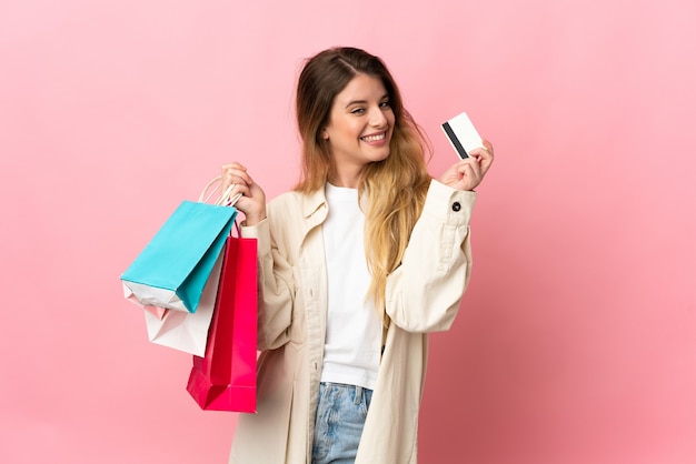 Młoda blond kobieta w tle trzymając torby na zakupy i kartę kredytową