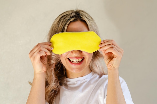 Młoda blond kobieta z maską do spania, bawiąc się i relaksując w domu Koncepcja odnowy biologicznej i chłodzenie jakość snu dobranoc bezsenność relaks zdrowy sen