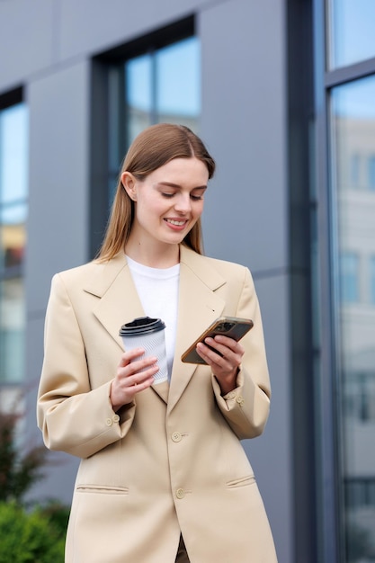 Młoda blondynka na tle centrum biznesowego centrum biznesowego Portret udanego startupu Smartphone kawa casual suit