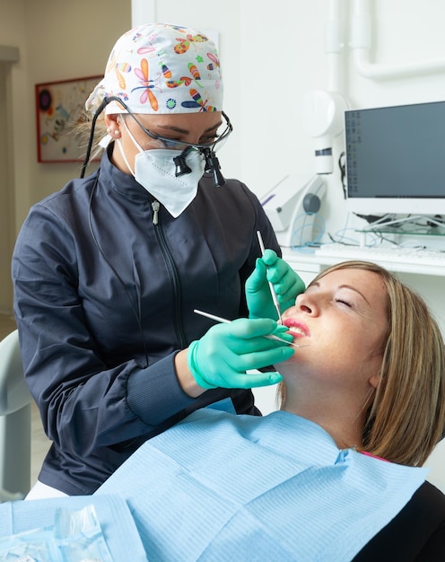 Młoda blondynka pacjentka z otwartymi ustami badająca kontrolę dentystyczną w gabinecie dentystycznym