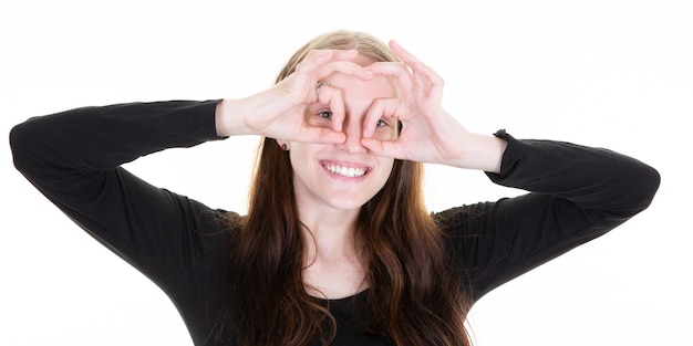 Zdjęcie młoda blondynka robi ok gestykulacyjne okulary palcami dłoni uśmiechniętym okiem patrzącym przez palec ze szczęśliwą twarzą