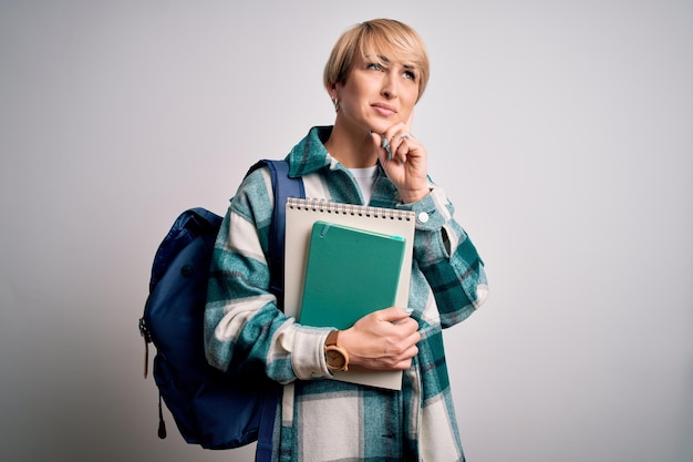 Młoda blondynka studentka z krótkimi włosami, nosząca plecak i trzymająca książki uniwersyteckie, poważna twarz, myśląca o bardzo zdezorientowanym pomyśle
