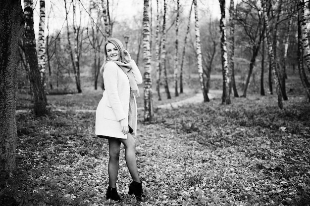 Młoda blondynka w różowym płaszczu pozowała w jesiennym parku