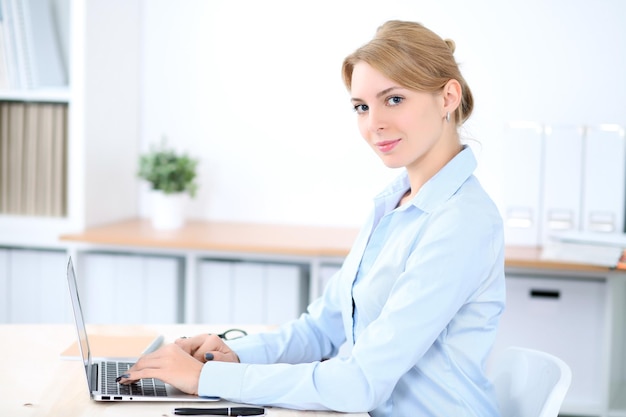 Młoda blondynki biznesowa kobieta z laptopem w biurze. Pomysł na biznes.