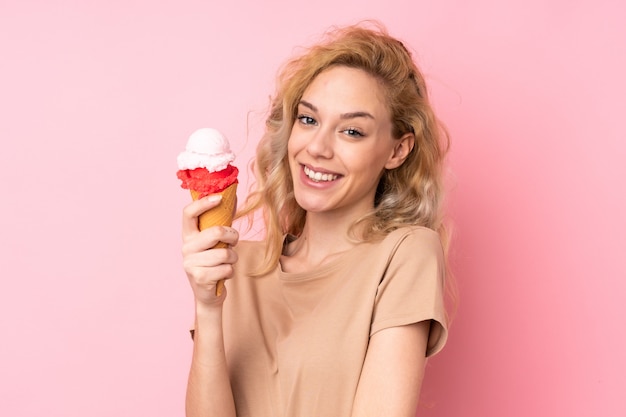 Młoda blondynki kobieta trzyma kornetowego lody na menchiach