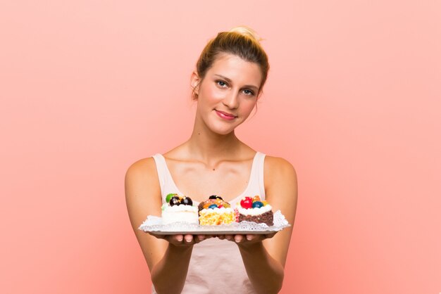 Młoda blondynki kobieta trzyma mnóstwo różnych mini torty