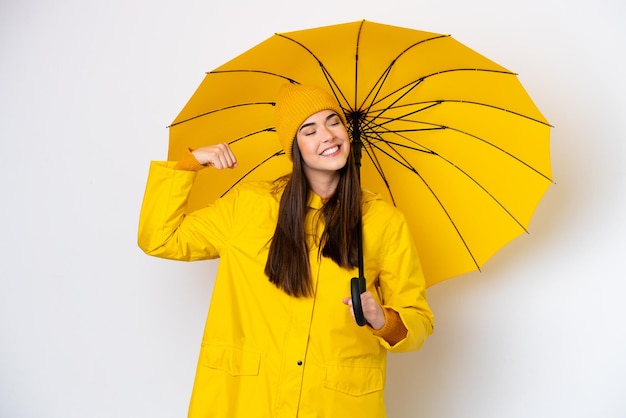 Młoda Brazylijka z płaszczem przeciwdeszczowym i parasolem na białym tle robi silny gest
