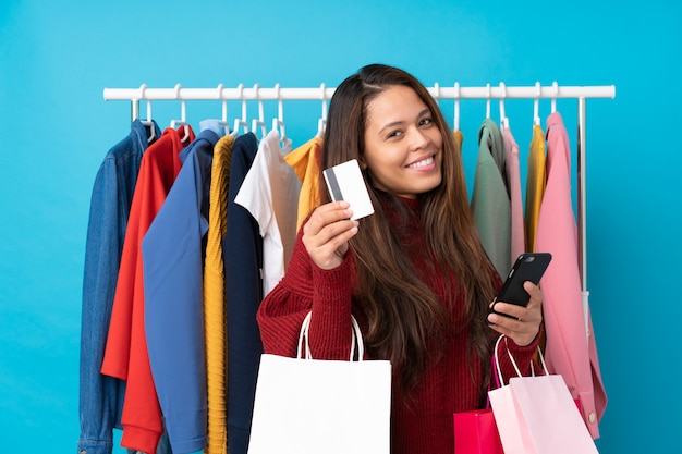 Młoda Brazylijska dziewczyna z torba na zakupy i kredytową kartą w sklepie nad odosobnionym błękitem