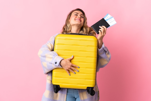 Młoda brazylijska kobieta odizolowywająca na różowo w wakacje z walizką i paszportem