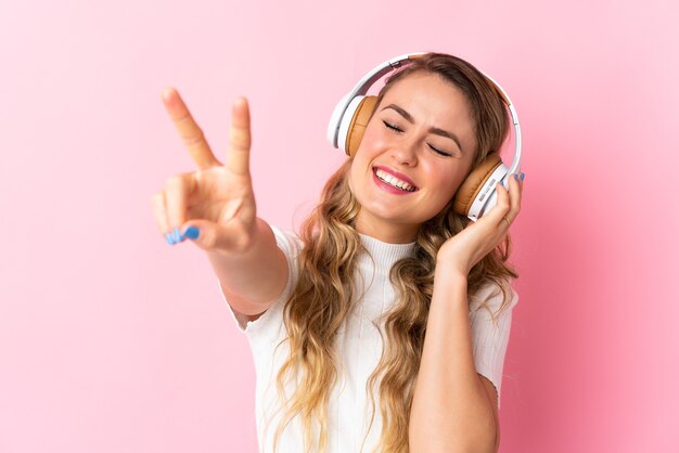 Młoda brazylijska kobieta odizolowywająca na różowym słuchaniu muzyki i śpiewu