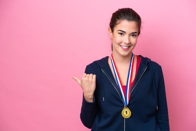 Młoda brazylijska sportowa kobieta z medalami na białym tle na różowym tle skierowana w bok, aby zaprezentować produkt