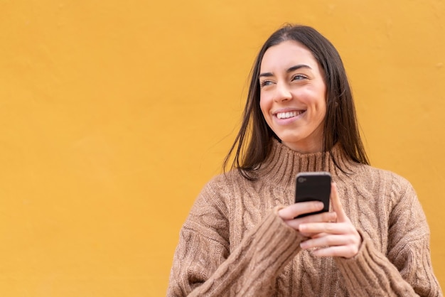 Młoda brunetka kobieta na zewnątrz za pomocą telefonu komórkowego i patrząc w górę