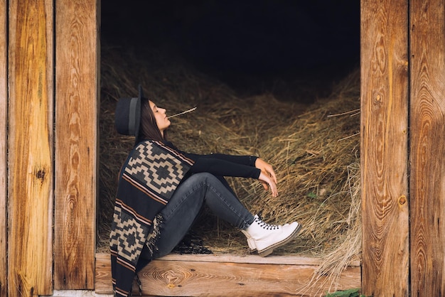 Młoda brunetka kobieta siedzi w stodole Country style