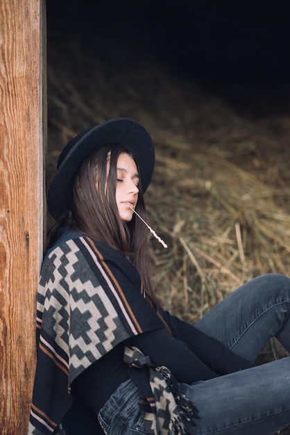 Młoda brunetka kobieta siedzi w stodole Country style